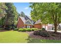 Beautiful brick home featuring a landscaped yard, manicured bushes, and a lovely, shady tree at 13995 Mariners Cv, Alpharetta, GA 30005