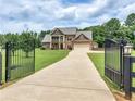 View of the home with a gated driveway and large front lawn at 3905 Pointer Rd, Loganville, GA 30052