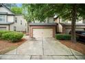 Townhome featuring a two-car garage, lush landscaping, and a paved driveway, with nearby parking visible at 1278 Houndslake Dr, Marietta, GA 30008