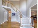 Foyer featuring a carpet staircase with oak banister and hardwood floors, leading to upper level and bedrooms at 1620 Silverleaf Way, Alpharetta, GA 30005