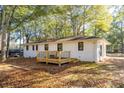 Rear view of house with a new deck, windows with black trim, and surrounded by mature trees at 409 Colette Ln, Social Circle, GA 30025