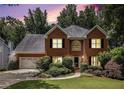 Charming brick two-story home featuring a well-manicured lawn and attached two-car garage at dusk at 1884 Whitehawk Ct, Lawrenceville, GA 30043
