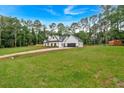 Expansive grassy lot featuring a stunning white farmhouse with a dark garage and fenced perimeter at 3088 Hiram Sudie Road, Hiram, GA 30141