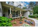 Inviting covered front porch with rocking chairs, brick columns, and landscaped garden beds at 188 Macedonia Rd, White, GA 30184