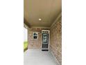 Covered porch with brick pillars and siding, a small window, and a dark front door with glass at 1961 Ecoland Dr, Grayson, GA 30017