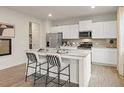Bright kitchen boasts white cabinets, stainless appliances, granite counters, and a center island with stool seating at 8502 Polston Lot 144 Pl, Douglasville, GA 30134