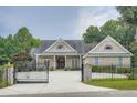 Charming brick home featuring an open gate with manicured landscaping, and an elegant, arched double-door entrance at 4829 Moon Rd, Powder Springs, GA 30127
