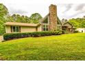 The ranch-style home features a stone chimney and well-maintained landscaping on a green lawn at 130 Brooklet Way, Brooks, GA 30205