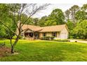 Inviting front exterior of a ranch-style home with well-kept lawn, stone chimney, and covered porch at 130 Brooklet Way, Brooks, GA 30205
