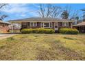 Quaint brick ranch featuring an open carport and established shrubs at 965 Laurel St, Morrow, GA 30260