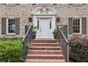 Elegant brick stairs leading to a front door with decorative molding, planters, and stylish sconces at 5349 Forest Springs Dr, Dunwoody, GA 30338