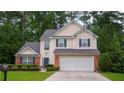 Inviting two-story home featuring a manicured lawn, brick accents, and an attached two-car garage at 1332 Chandler Cove Way, Grayson, GA 30017