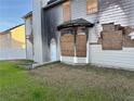 Backyard view of gray home with boarded-up windows, fire damage, and a white door at 1980 Piedmont Pointe Dr, Lithonia, GA 30058