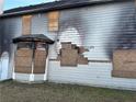 Damaged siding of gray home with boarded-up windows and evidence of fire damage at 1980 Piedmont Pointe Dr, Lithonia, GA 30058
