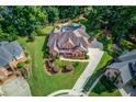 Aerial shot of a brick home, revealing a backyard pool, mature trees, and manicured lawns at 3217 Aberrone Pl, Buford, GA 30519