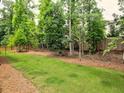 Large backyard with a mix of grass and pine straw, surrounded by a wood fence and mature trees at 913 Sunny Meadows Ln, Marietta, GA 30062
