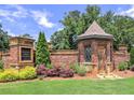 Walton Creek Estates entrance with brick walls, a small guard building with a turret roof, and lush landscaping at 913 Sunny Meadows Ln, Marietta, GA 30062