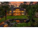 Expansive backyard at dusk with lush greenery, a charming pond, and a spacious deck, illuminated by exterior lights at 1865 Mason Mill Rd, Decatur, GA 30033