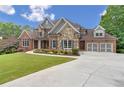 Beautiful home featuring brick and stone accents, a three-car garage, and a well-maintained front yard at 5114 Brendlynn Dr, Suwanee, GA 30024