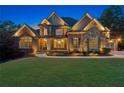 Charming two-story home at dusk showcasing brick and stone exterior, lush lawn, and landscaped garden at 5114 Brendlynn Dr, Suwanee, GA 30024