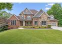Attractive two-story home with a combination of brick and stone, surrounded by a lush, green lawn at 5114 Brendlynn Dr, Suwanee, GA 30024