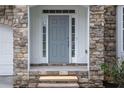 Close-up of a welcoming front entrance with a stone surround and a stylish gray door at 1722 Preserve Creek Way, Loganville, GA 30052