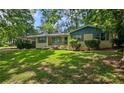 Charming one-story home featuring yellow brick, a landscaped front yard, mature trees, and covered parking at 1729 Norden Rd, Riverdale, GA 30296