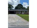 Charming single-story brick home with a long driveway and attached carport, nestled among mature trees at 6192 Meadowbrook Dr, Norcross, GA 30093