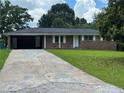 Charming single-story brick home with a long driveway and attached carport, nestled among mature trees at 6192 Meadowbrook Dr, Norcross, GA 30093