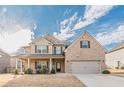 Inviting two-story brick home with a welcoming front porch and a manicured lawn and beautiful skies at 879 Tranquil Way, Hampton, GA 30228