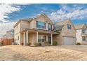 Lovely brick home featuring a covered porch, manicured landscaping, and a two-car garage with cloudy skies at 879 Tranquil Way, Hampton, GA 30228