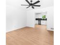Spacious living room with hardwood floors, neutral walls, and a ceiling fan that flows into the modern kitchen at 264 Howell Sw Ter, Atlanta, GA 30331