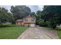 Split-level home with stone facade, a driveway leading to an attached garage, and a lawn at 3778 Glen Mora Dr, Decatur, GA 30032