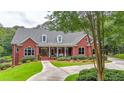 Charming red brick home with a manicured lawn, covered porch with columns, and mature trees in a tranquil setting at 750 Old Loganville Road Southwest, Loganville, GA 30052