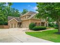 View of a three-car garage and driveway with mature landscaping around this home at 217 Heritage Town Pkwy, Canton, GA 30115