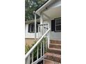 View of the house's inviting entrance, showcasing a small covered porch with white railings and brick steps at 6197 Union Grove Rd, Lithia Springs, GA 30122