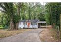 Charming home featuring a covered parking spot and a welcoming front porch with an orange door at 2437 Clarissa Nw Dr, Atlanta, GA 30318