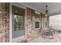 Inviting front porch featuring brick flooring, seating, and decorative lighting for relaxing outdoor enjoyment at 4130 Millbrook Ct, Suwanee, GA 30024