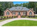 Charming single-story brick home featuring a lush lawn, circular driveway, and manicured landscaping at 2065 Innsfail Dr, Snellville, GA 30078