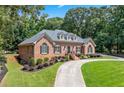 Attractive single-story brick home with circular driveway, lush lawn and mature trees at 2065 Innsfail Dr, Snellville, GA 30078