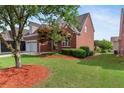 View of the house, surrounded by lush greenery, red brick, and a well-maintained lawn at 1979 Spivey Village Dr, Jonesboro, GA 30236