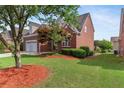 View of the house, surrounded by lush greenery, red brick, and a well-maintained lawn at 1979 Spivey Village Dr, Jonesboro, GA 30236