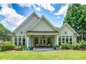 Backyard view featuring a covered patio with outdoor seating, lush green lawn, and mature landscaping at 825 Chalet Hls, Mcdonough, GA 30253