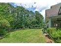View of a well-maintained backyard with a large grassy area, mature trees, and colorful flower beds at 825 Chalet Hls, Mcdonough, GA 30253