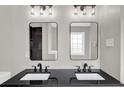 Modern bathroom featuring a black granite countertop with dual sinks and mirrors, alongside elegant lighting at 583 Whitaker St, Atlanta, GA 30318