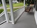 Inviting front porch featuring a gray deck, white railing and a relaxing swing at 6280 Autry Mill Rd, Cumming, GA 30028