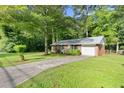 Well-maintained single story brick home with long driveway and lush green lawn in a wooded setting at 6671 Gano Dr, Riverdale, GA 30274