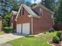 Side view of brick home with a two car garage and well-kept lawn at 2670 Henderson Chase Ct, Tucker, GA 30084