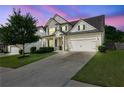 Stunning two-story home showcases a pristine lawn, two-car garage and picturesque dusk sky at 3940 Frasier Dr, Cumming, GA 30028