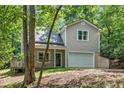 Home with a one-car garage and cozy front porch, framed by lush trees and natural landscaping at 3255 Marine Rd, Cumming, GA 30041